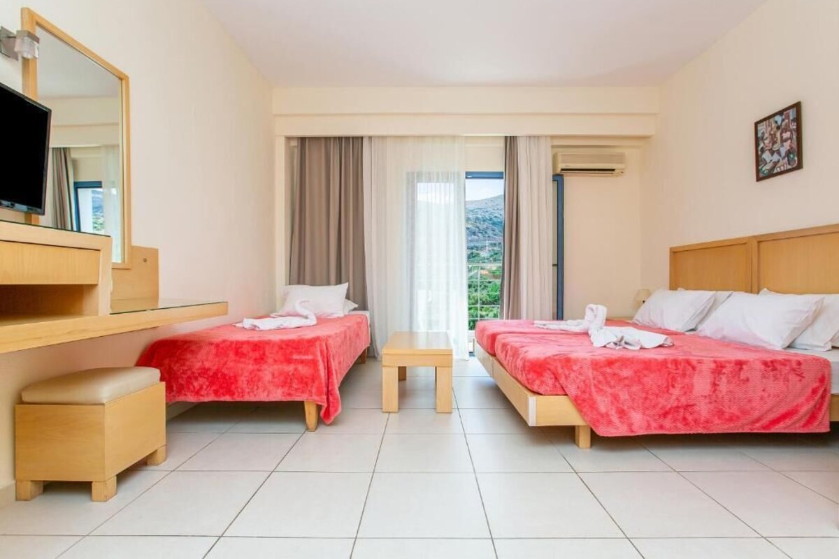Une chambre d’hôtel avec deux lits, un bureau, une chaise et un téléviseur.