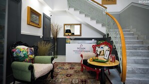 A reception area with a staircase, a reception desk, and two chairs. - Siculea Home  (Adrano)