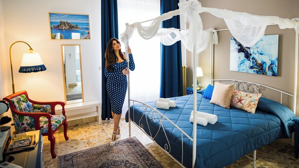 A hotel room with a bed, a chair, a desk, and a bedside table. - Siculea Home  (Adrano)