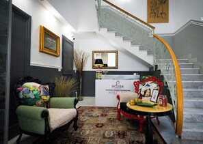 A reception area with a staircase, a reception desk, and two chairs. - Siculea Home  (Adrano)