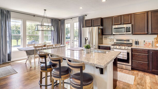 A spacious kitchen with a large island, dark wooden cabinets, stainless steel appliances, and a dining area with a table and chairs. - 4 Mi to The District: Family Home w/ Tennis Access (South Jordan)