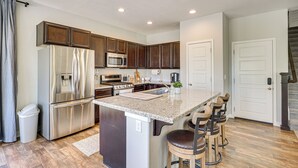 A modern kitchen with stainless steel appliances, a granite countertop, and wooden cabinets. - 4 Mi to The District: Family Home w/ Tennis Access (South Jordan)