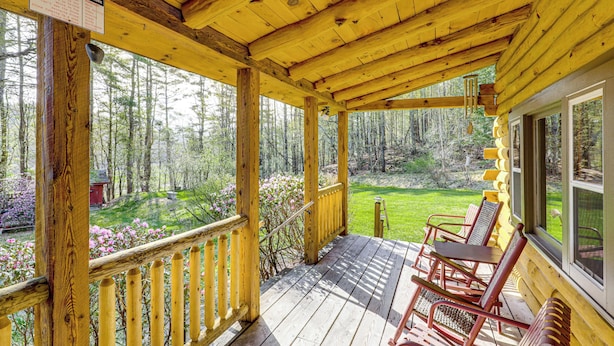 Une terrasse en bois avec un panneau indiquant la présence d’une station météorologique, une vue sur la forêt et des sièges d’extérieur.