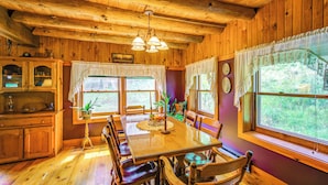 L’intérieur d’un chalet en bois, avec une table à manger, des chaises et un lustre.