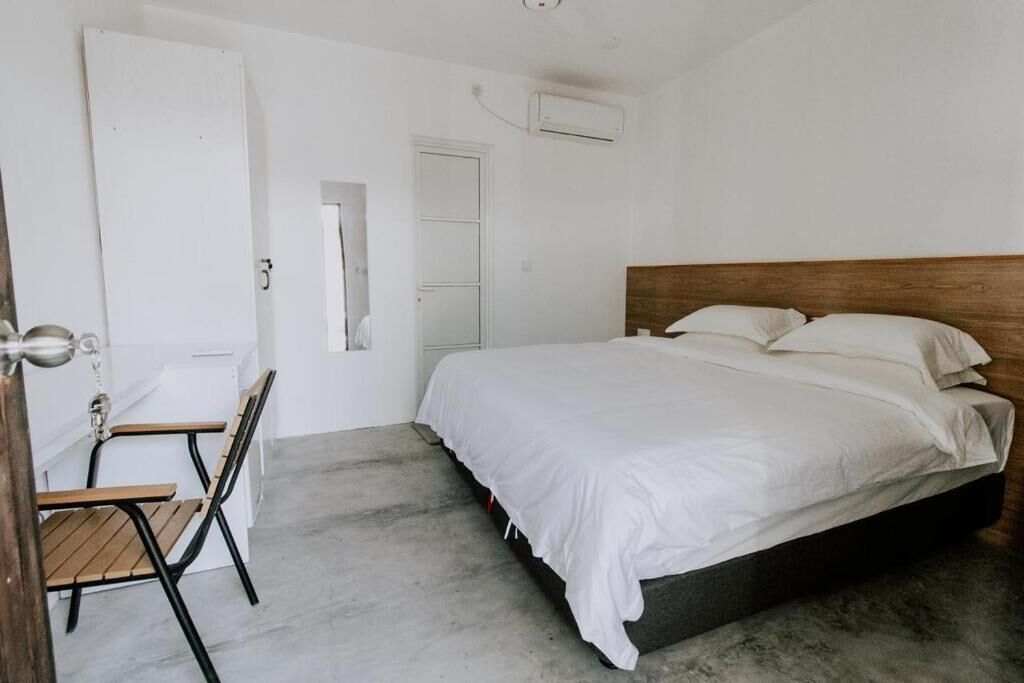 A bedroom with a bed, a chair, and a door.