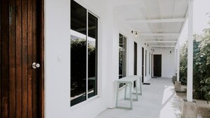 A corridor with large windows, a wooden door, and a bench. - Moro Kihaadhoo (Kihaadhoo)
