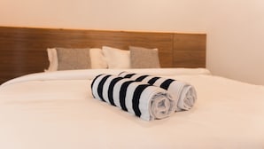 A neatly made bed with a striped towel, a wooden headboard, and two pillows. - Moro Kihaadhoo (Kihaadhoo)