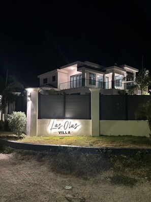 A modern villa with a well-lit entrance and a sign that reads 'Las Olas Villa.'