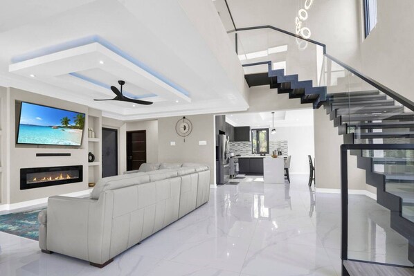Un salon moderne avec un grand canapé blanc, un téléviseur à écran plat et une cheminée.