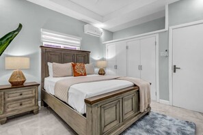 A bedroom with a bed, nightstands, a wardrobe, and a large window.