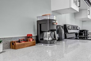 Una cocina moderna con cafetera, hervidor y estufa.