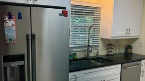 Une cuisine équipée d’un réfrigérateur en acier inoxydable, d’un distributeur d’eau et de meubles de rangement blancs.