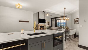 A modern kitchen with a large island, dark cabinetry, and a fireplace.