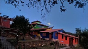 A multi-story building with a red roof, surrounded by greenery and a stone wall. - Casa do Geninho Pousada e Camping  (Lima Duarte)