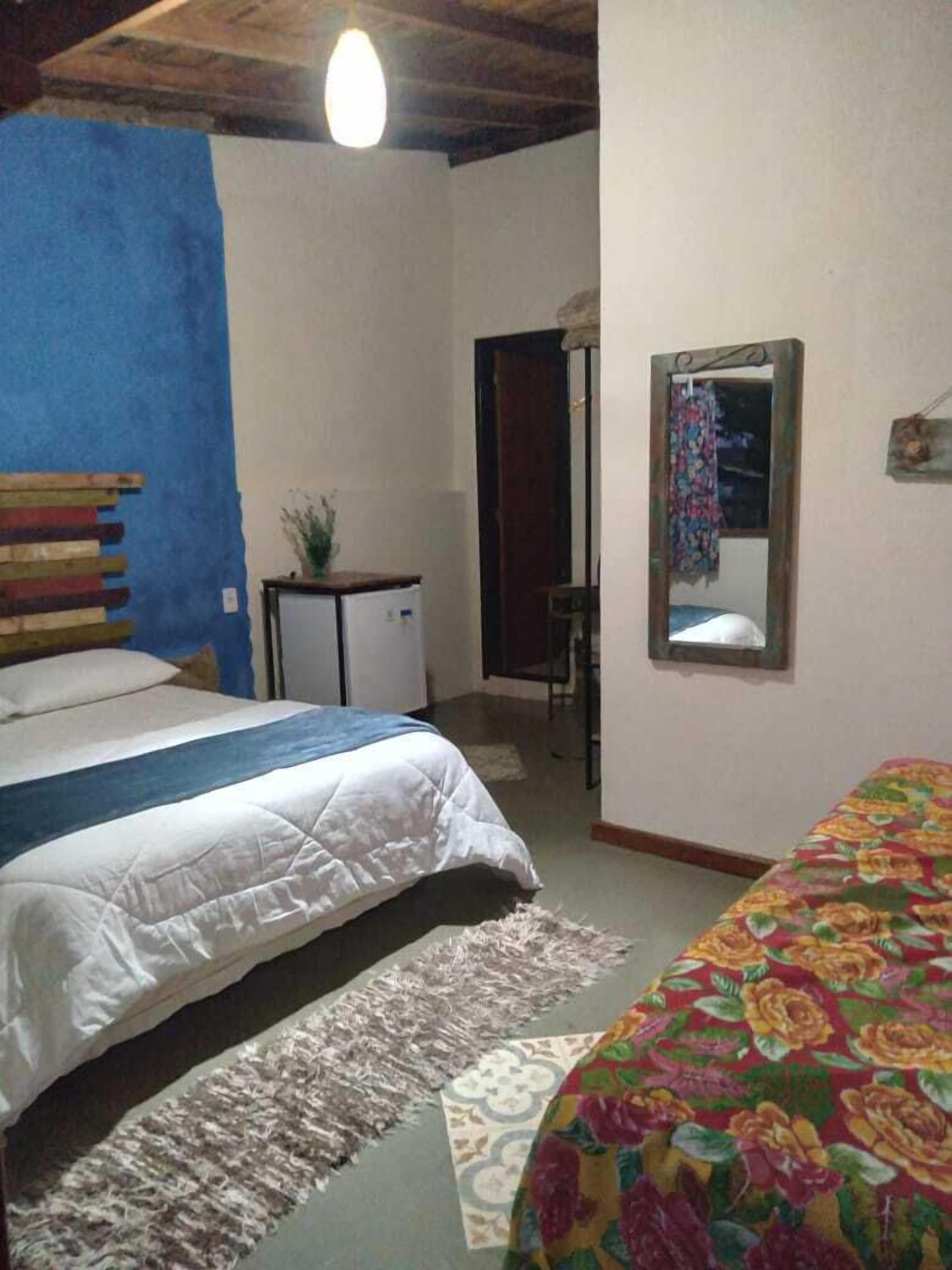 A bedroom with a bed, a small desk, a mirror, and a blue accent wall.