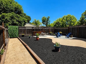 A backyard with a wooden fence, outdoor furniture, and potted plants.