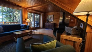 A cozy cabin interior with a sofa, coffee table, and lamp. - Pine Camp*Seaplane/Boat Dock*Lake/Mountain View*Kayaks (Greenville)