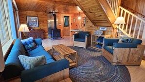 A cozy cabin interior with a wooden interior, a fireplace, a sofa, and a dining table. - Pine Camp*Seaplane/Boat Dock*Lake/Mountain View*Kayaks (Greenville)