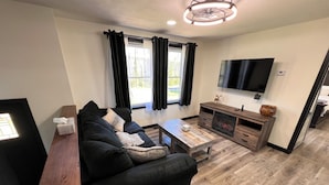 Ein modernes Wohnzimmer mit einem schwarzen Sofa, einem Holztisch und einem Kamin.