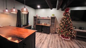 Eine moderne Küche mit Holztresen, Pendelleuchten, einer integrierten Kaffeemaschine und einem Weihnachtsbaum.