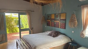 A bedroom with a bed, a bench, a small stool, and a macramé wall hanging. - BEACH FRONT PROPERTY
Serene 3-bedroom house with AC in Skhirat (Skhirat)