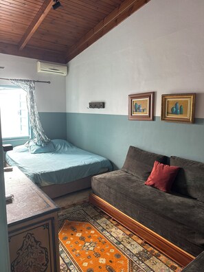Ein Zimmer mit einem Bett, einer Couch, einem gemusterten Teppich und zwei gerahmten Bildern an der Wand.