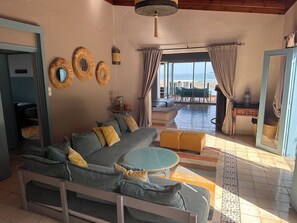 A living room with a sofa, a round table, and a view of the beach through large windows. - BEACH FRONT PROPERTY
Serene 3-bedroom house with AC in Skhirat (Skhirat)