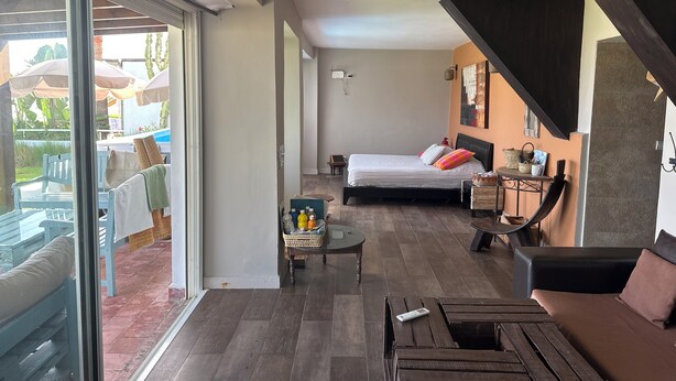 A modern bedroom with a large bed, a small table, and a sofa. There is a sliding glass door leading to an outdoor area with umbrellas. - BEACH FRONT PROPERTY
Serene 3-bedroom house with AC in Skhirat (Skhirat)