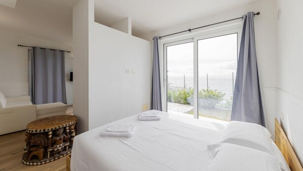 Una camera da letto moderna con un letto grande, una poltrona e un tavolino rotondo.