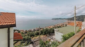 Una cittadina costiera con edifici dalle tegole color terracotta, vista sul mare e cielo sereno.