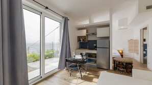 Un appartamento moderno con zona pranzo, angolo cottura e un'ampia porta-finestra che si apre su un balcone.
