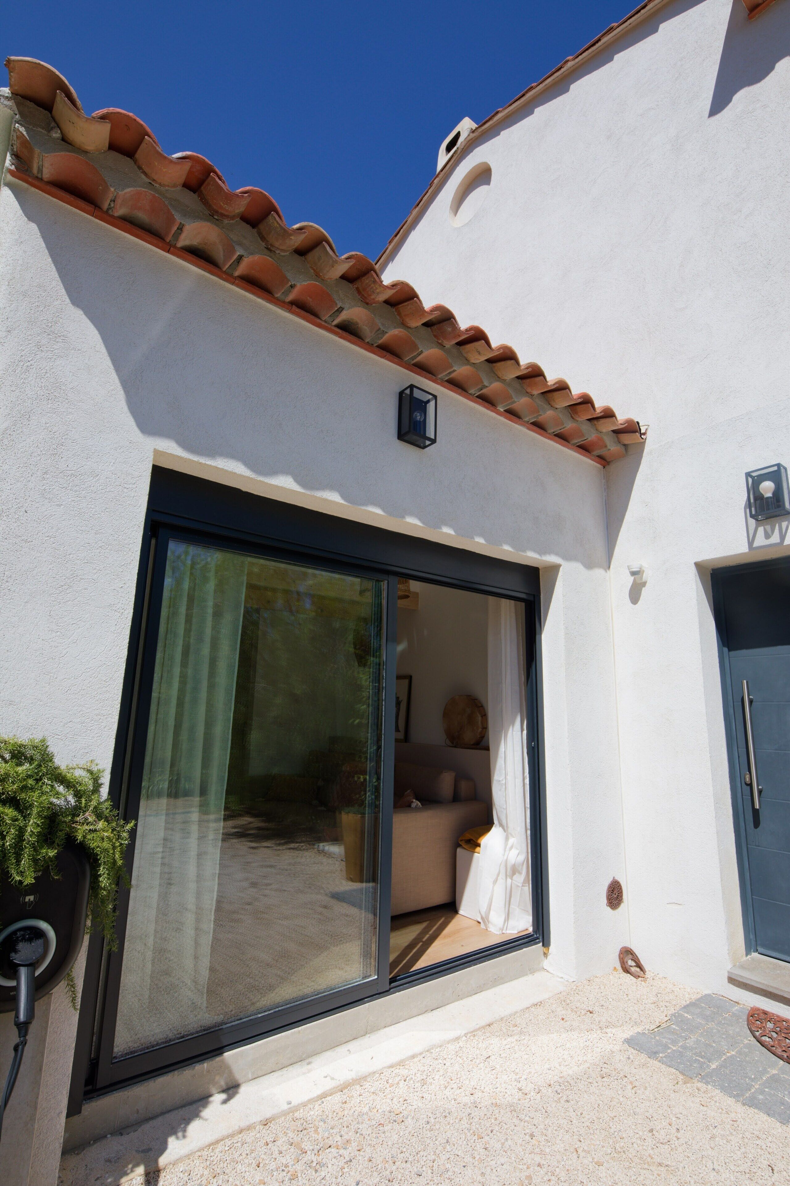 A building with a tiled roof, a large sliding glass door, and a blue door.