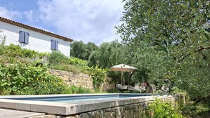 A stone wall surrounding a swimming pool with a patio area and outdoor furniture. - Separate room with pool access (Opio)