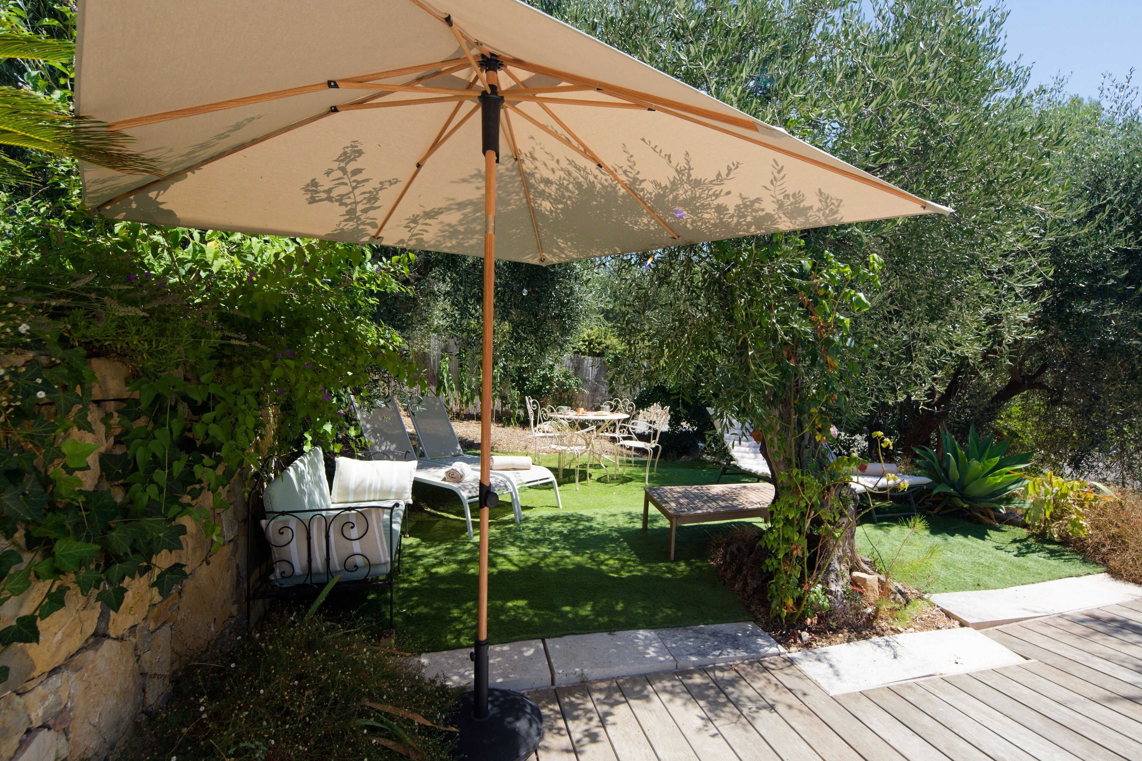 A patio with a wooden deck, a table with chairs, and a large umbrella.