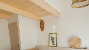 A bedroom with a large bed, wooden beams, a woven light fixture, a framed artwork, and a round decorative item on a shelf. - Separate room with pool access (Opio)