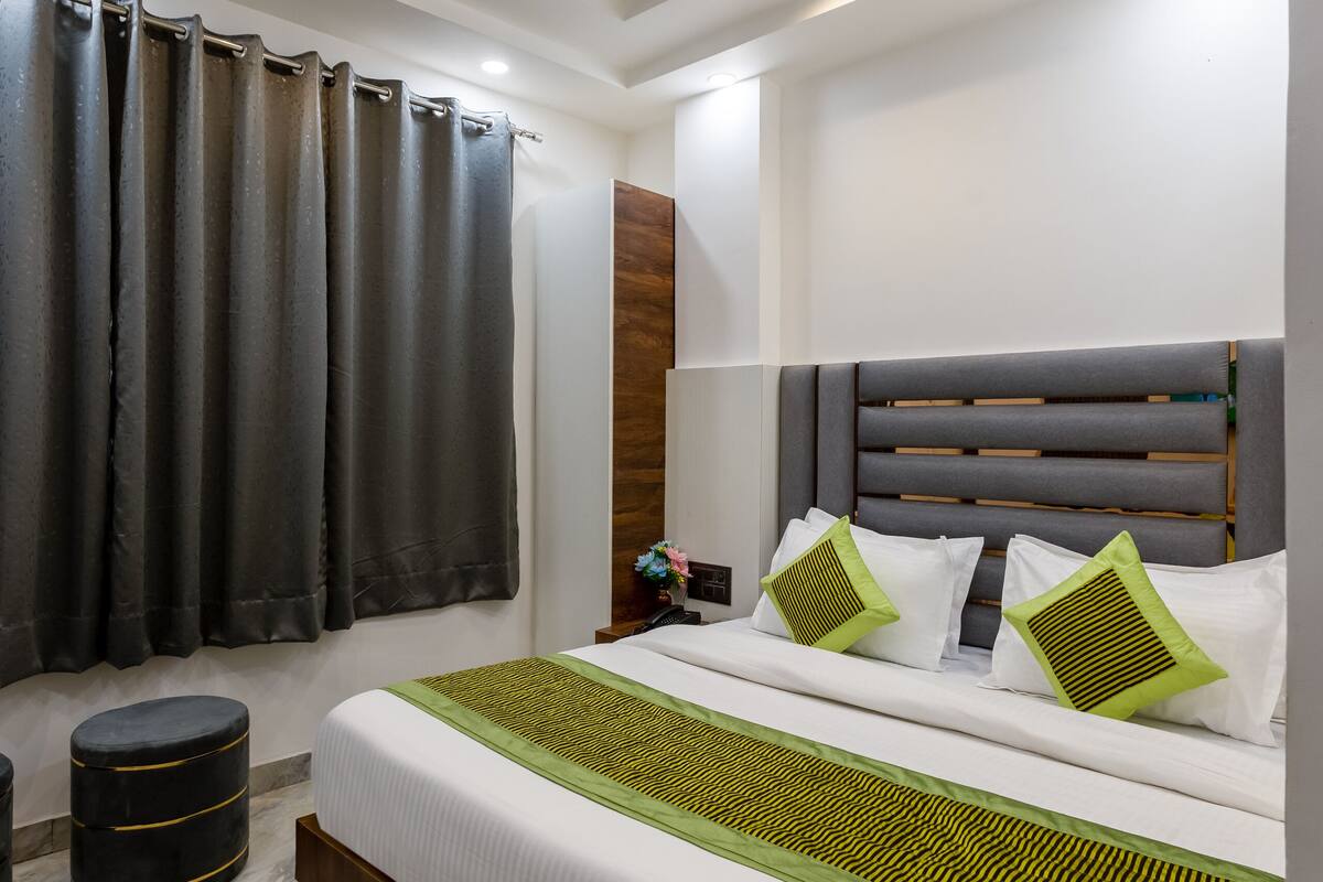 A modern bedroom with a large bed, a ceiling fan, and a window with curtains.