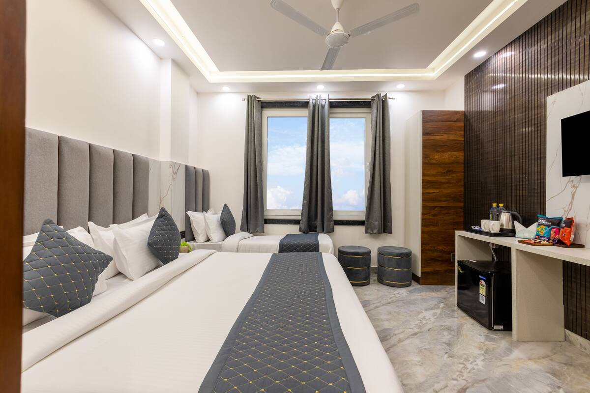 A modern hotel room with a large bed, a desk, and a ceiling fan.