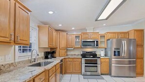 Una cocina moderna con armarios de madera, electrodomésticos de acero inoxidable y una encimera de granito.