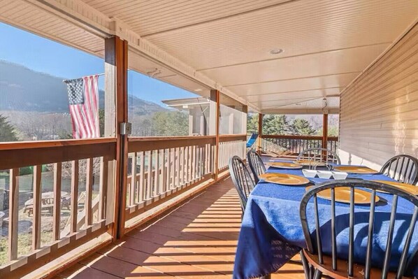 Un patio techado al aire libre con una mesa lista para comer, vistas a las montañas y una bandera estadounidense.
