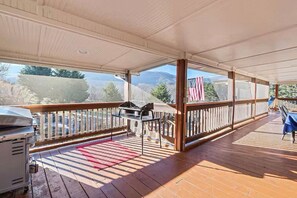 An outdoor covered patio with a grill, seating area, and a view of the mountains.