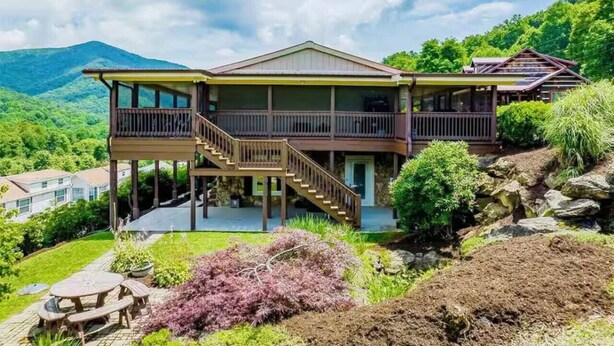 Una casa de dos pisos con balcón, escaleras y vista del paisaje circundante.