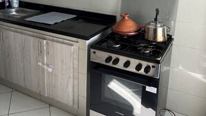A kitchen with light wood cabinets, a stainless steel stove, and a black countertop.