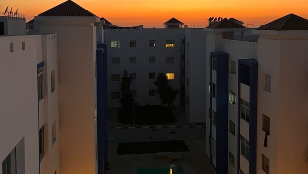 A courtyard with a swimming pool, surrounded by modern buildings with flat roofs and multiple windows.