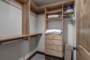 Ein begehbarer Kleiderschrank mit Holzböden, Schubladen und einer Kleiderstange.