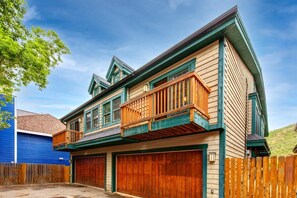 A two-story house with a balcony, a garage, and a wooden fence.