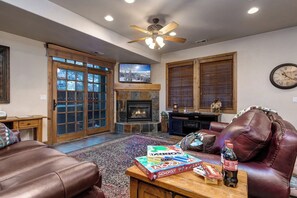 Ein Wohnzimmer mit Kamin, Ledermöbeln, einem Fernseher und einem Monopoly-Spiel.