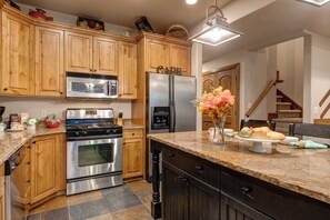 A kitchen with wooden cabinets, stainless steel appliances, a granite countertop, and a vase with flowers.