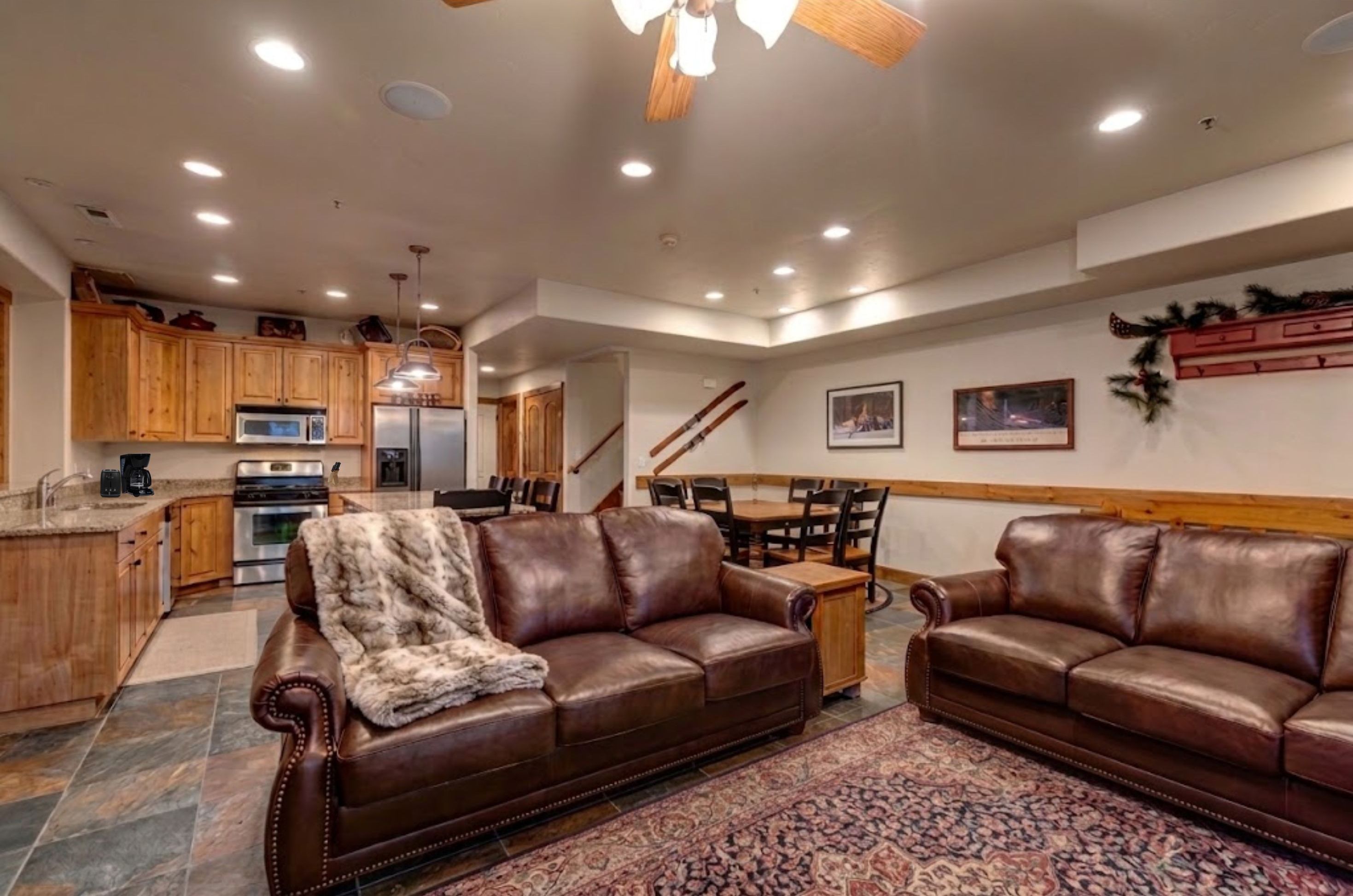 A spacious living area with leather sofas, a dining table, and a kitchen in the background.