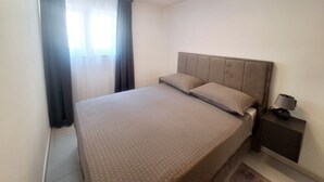 A bedroom with a bed, curtains, a nightstand, and a lamp.