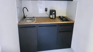 A compact kitchen with a sink, stove, and black cabinets.